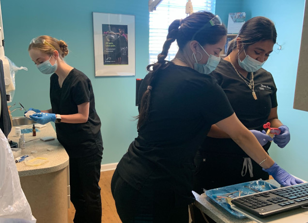 {{ school.name }} students working with dental tools in class {{ school.name }} students working with dental tools in class