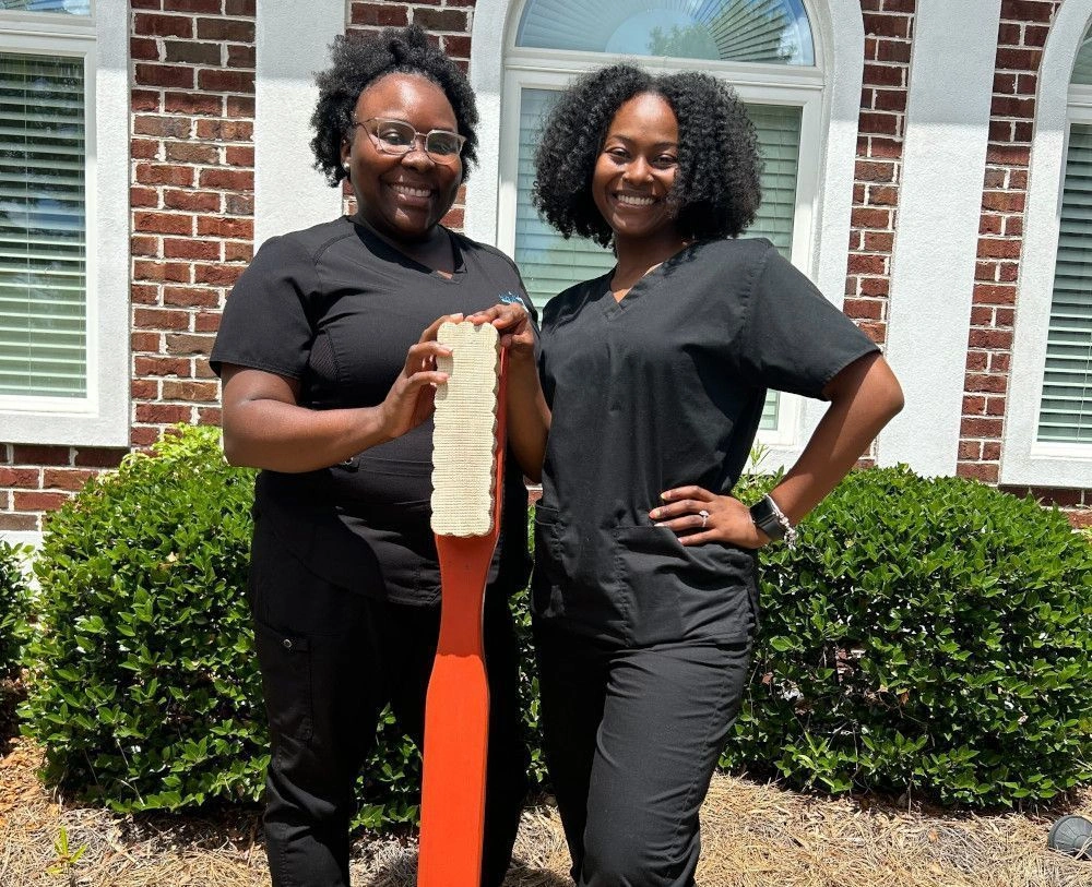 {{ school.name }} students posing with life size toothbrush outside of the facility {{ school.name }} students posing with life size toothbrush outside of the facility